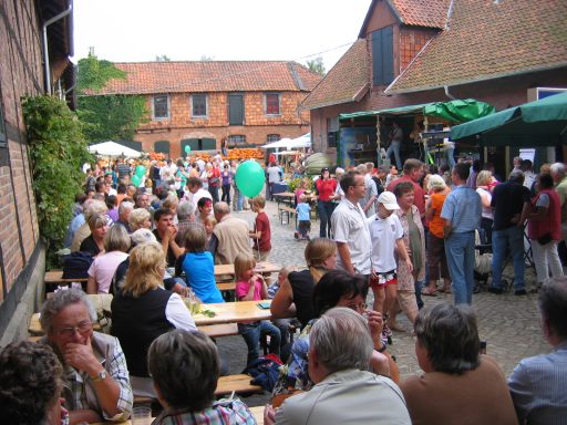 Blick auf einen Bauernhof mit Kürbisfest und vielen Besuchern die z. T. sitzen und flanieren