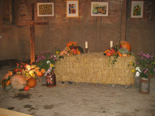 Ein mit Kürbissen, Blumen und Kerzen dekorierter Tisch aus Stroh.