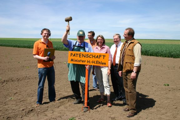 Landwirtschaftsminister Hans- Heinrich Ehlen schlägt mit einem großen Holzhammer ein Patenschaftsschild für seinen Kürbis in den Boden. 