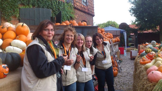 fünf Frauen mit gleichen Westen - alles Helfer beim Kürbisfest- vor bunter Kürbiskulisse